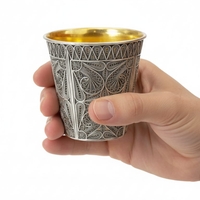 A hand holding a pure silver Kiddush cup, 