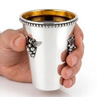 Hand holding a pure silver Kiddush cup, handmade with grape decoration