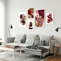 סט תמונות קנבס בגווני בורדו, ורוד וזהב עם פורטרט נשי ועיצוב אבסטרקטי מודרני תלוי מעל ספה בהירה בסלון מעוצב.