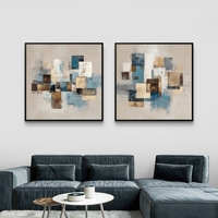 זוג תמונות קנבס מרובעות בעיצוב אבסטרקטי גאומטרי בגווני כחול, בז’ וחום מעל ספה בסלון מודרני