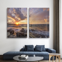 זוג תמונות זכוכית עם שקיעה מעל הים, סלעים וגלים בתנועה עדינה בעיצוב רגוע ואלגנטי לקיר הבית