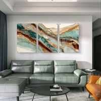 תמונת זכוכית מחולקת לשלושה חלקים בעיצוב שיש אבסטרקטי בגווני טורקיז, חום וזהב תלויה מעל שולחן אוכל מודרני.