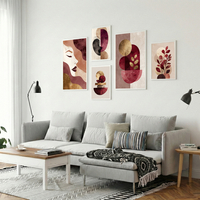סט תמונות קנבס מודרני בגווני בורדו, ורוד וזהב עם דמויות נשיות וצורות גיאומטריות תלוי מעל ספה בהירה בסלון מעוצב.