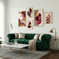 סט תמונות קנבס מודרני בגווני בורדו, ורוד וזהב עם דמויות נשיות וצורות גיאומטריות תלוי מעל ספה בהירה בסלון מעוצב.