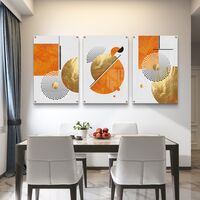 תמונת זכוכית מחולקת לשלושה חלקים בעיצוב גיאומטרי בגווני כתום וזהב תלויה מעל ספה מודרנית בסלון.