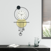 שעון קיר מעוצב בסגנון מודרני עם צורות גאומטריות, מסגרת עגולה, מטוטלות דקורטיביות וגימור אלגנטי בגווני שחור, לבן וזהב, תלוי על קיר בהיר.