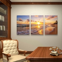 שלישיית תמונות זכוכית עם שקיעה זהובה על חוף הים, גלים עדינים וצבעים חמים בעיצוב רגוע ואלגנטי לסלון