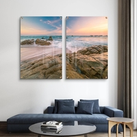 זוג תמונות זכוכית עם חוף סלעי וגלים בתנועה רכה, שמיים פסטליים ועיצוב רגוע ואלגנטי לקיר הבית