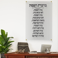 תמונת זכוכית שקופה עם כיתוב ברכת העסק בצבע שחור תלויה על קיר לבן במשרד יוקרתי עם שולחן עץ כהה, כסא מנהלים וצמח ירוק בצד.