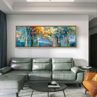 תמונת קנבס פנורמית של יער בגווני טורקיז וזהב מעל ספה אפורה.