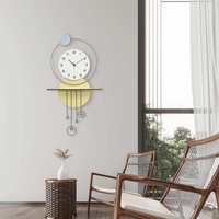 שעון קיר מעוצב בסגנון מודרני עם צורות גיאומטריות, מסגרת עגולה, מטוטלות דקורטיביות וגימור אלגנטי בגווני זהב, אפור ולבן, תלוי על קיר בעיצוב מינימליסטי.