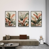 סט של שלוש תמונות קנבס עם איורי עלים בוטניים בגווני ירוק, שמנת וחום, בעיצוב עדין ומודרני לסלון.