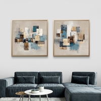 זוג תמונות קנבס מרובעות בעיצוב אבסטרקטי גאומטרי בגווני כחול, בז’ וחום מעל ספה בסלון מודרני