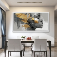 קנבס מודרני מעל ספה עם פנים נשיות אבסטרקטיות ומשיחות זהב יוקרתיות על רקע אפור