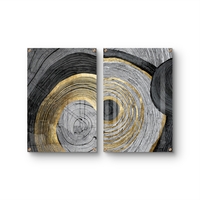 סט תמונות זכוכית זוג בעיצוב אבסטרקטי עם מעגלים קונצנטריים בגווני שחור, אפור ולבן עם נגיעות זהב מעל ספה מודרנית כחולה.