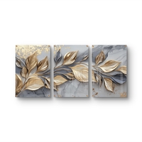 שלישיית תמונות זכוכית עם עלים מוזהבים בתנועה על רקע שיש אפור בעיצוב יוקרתי