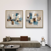 זוג תמונות קנבס מרובעות בעיצוב אבסטרקטי גאומטרי בגווני כחול, בז’ וחום מעל ספה בסלון מודרני