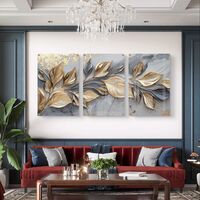 שלישיית תמונות זכוכית עם עלים מוזהבים בתנועה על רקע שיש אפור בעיצוב יוקרתי