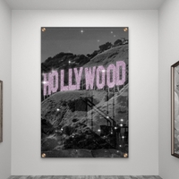 תמונת זכוכית של שלט HOLLYWOOD בגווני שחור־לבן עם אותיות ורודות מנצנצות, מתוך קולקציית NEXTGEN BY BAR של תכשיט לבית.