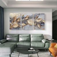 שלישיית תמונות זכוכית עם עלים מוזהבים בתנועה על רקע שיש אפור בעיצוב יוקרתי