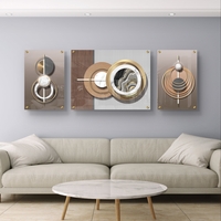 סט תמונות זכוכית מחולקות בעיצוב גאומטרי מודרני עם מעגלים, קווים וגווני זהב, עץ ואפור בסלון מעוצב