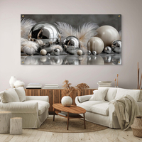 תמונת זכוכית לרוחב עם כדורי מתכת מבריקים ונוצות בגווני כסף ושמנת, בעיצוב יוקרתי ומודרני מתוך קולקציית תכשיט לבית.