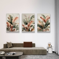 סט של שלוש תמונות קנבס עם איורי עלים בוטניים בגווני ירוק, שמנת וחום, בעיצוב עדין ומודרני לסלון.