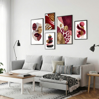 סט תמונות קנבס בגווני בורדו, ורוד וזהב עם פורטרט נשי ועיצוב אבסטרקטי מודרני תלוי מעל ספה בהירה בסלון מעוצב.