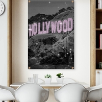 תמונת זכוכית של שלט HOLLYWOOD בגווני שחור־לבן עם אותיות ורודות מנצנצות, מתוך קולקציית NEXTGEN BY BAR של תכשיט לבית.