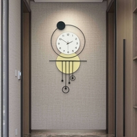 שעון קיר מעוצב בסגנון מודרני עם צורות גאומטריות, מסגרת עגולה, מטוטלות דקורטיביות וגימור אלגנטי בגווני שחור, לבן וזהב, תלוי על קיר בהיר.