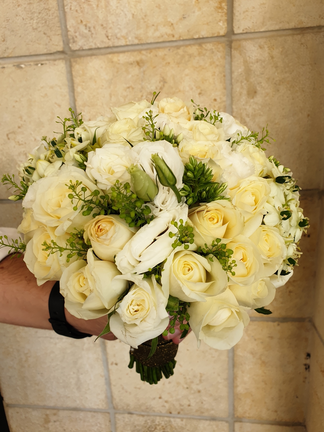 A white bridal bouquet with roses and lisianthus