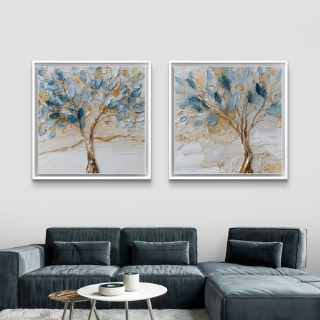 סט זוג תמונות קנבס מרובעות עם עצים אמנותיים בגווני כחול ותכלת ונגיעות זהב על רקע שמנתי, תלויות מעל ספה מודרנית.
