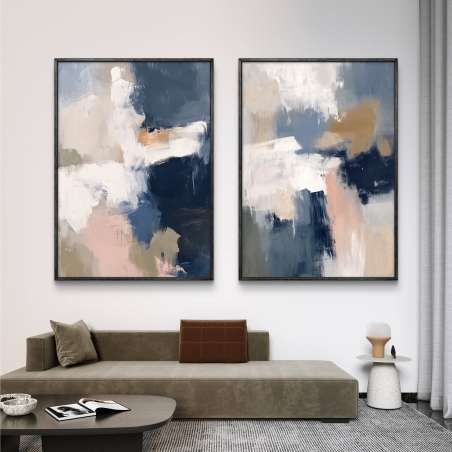זוג תמונות קנבס אבסטרקטיות מרובעות בגווני כחול כהה, לבן, בז' ורדרד, תלויות מעל ספה בחלל מעוצב בסגנון מודרני ונקי.