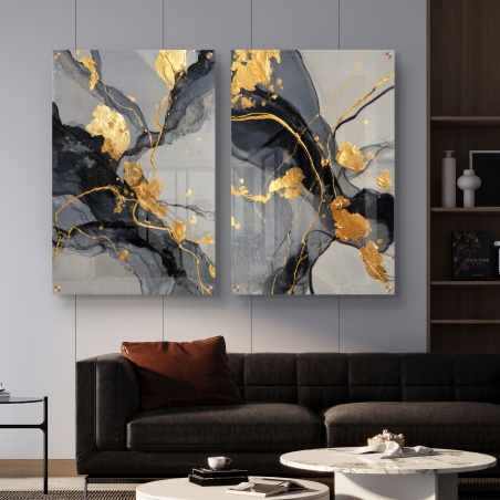 זוג תמונות זכוכית בגווני אפור, שחור וזהב תלויות על קיר כהה בין שתי כורסאות כחולות בסלון מודרני ואלגנטי.