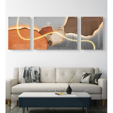 תמונת זכוכית מחולקת לשלושה חלקים עם נוף מדברי, קווים מוארים ואייל מוזהב, תלויה מעל ספה בסלון מודרני