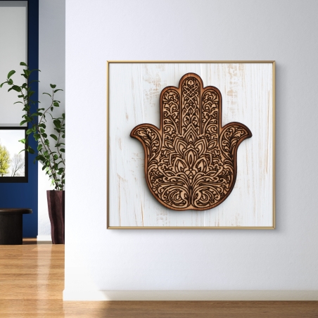 תמונת קנבס מרובעת עם חמסה מעוצבת בצבע עץ חום כהה על רקע לבן, תלויה מעל ספה מודרנית בגווני אפור כהה בסלון מעוצב בקו נקי.