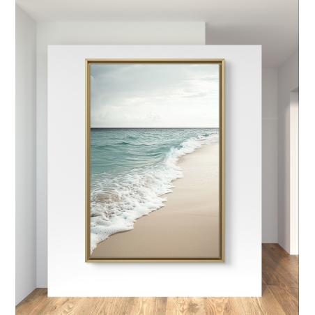 תמונת קנבס של חוף ים עם גלים שקטים נשברים על החול, תלויה על קיר ליד חלון וכורסה צהובה