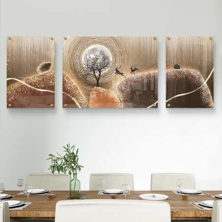 תמונה מחולקת על זכוכית עם ירח זוהר, איילים קופצים ונוף זהוב, תלויה מעל ספה מודרנית בסלון