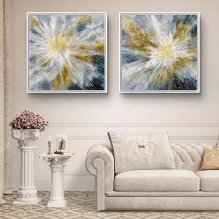 תמונת קנבס מרובעת בצבעי זהב, לבן, כחול ואפור בסגנון פיצוץ מופשט, תלויה מעל ספה מודרנית בגווני אפור כהה.