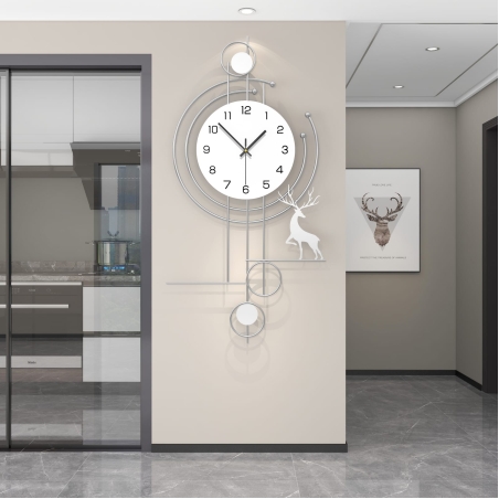 שעון קיר גדול בעיצוב מתכתי בצבע כסוף עם מוטיבים גיאומטריים ודמות אייל, תלוי על קיר בבית מודרני.