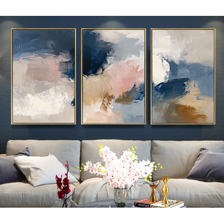 שלישיית תמונות קנבס בגוונים של בז', כחול כהה, ורוד וחרדל, תלויות מעל ספה בסלון מודרני עם עיצוב נעים וחמים.