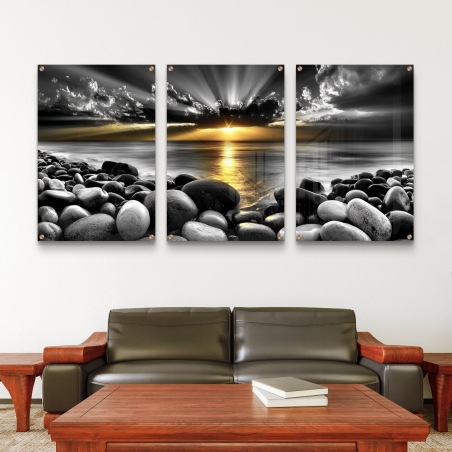 שלשה תמונות זכוכית של נוף חוף סלעי בשחור-לבן עם זריחה זהובה, עיצוב מודרני ודרמטי לקיר מהקולקציה של תכשיט לבית
