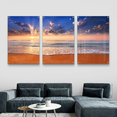 תמונת זכוכית מחולקת לשלושה חלקים עם נוף שקיעה בים, שמיים כחולים וחוף זהוב