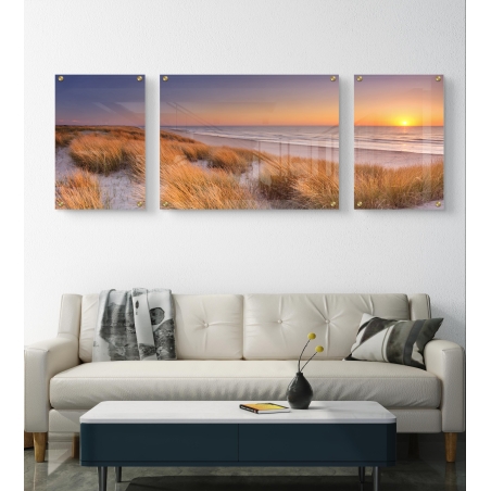 תמונת זכוכית מחולקת המציגה דיונות חול עם עשב זהוב ושקיעה מרגיעה מעל הים – בהדפסה חלקה באיכות גבוהה.