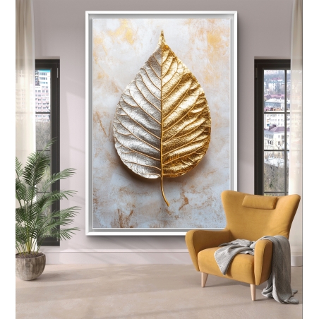 תמונת קנבס עם הדפס חלק של עלה בזהב וכסף, תלויה בפינת קריאה מודרנית עם כורסה בגוון חרדל.