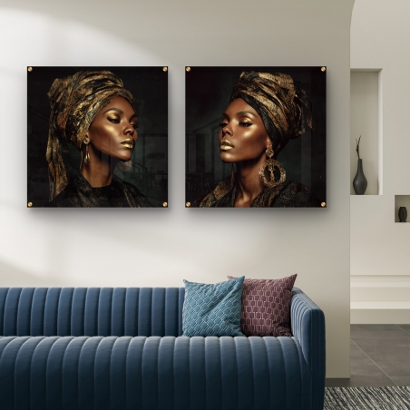 זוג תמונות זכוכית מרובעות עם נשים אפריקאיות עטופות במטפחות שחורות וזהובות תלוי על קיר סלון מודרני