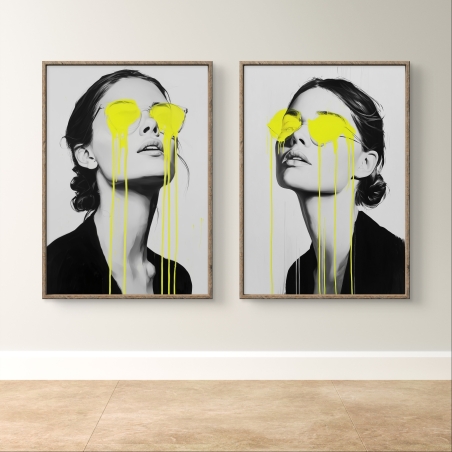 זוג תמונות קנבס של דמות נשית בשחור-לבן עם צבע ניאון צהוב מטפטף מהעיניים, תלויה מעל ספה מודרנית בחלל מעוצב בסגנון מינימליסטי.