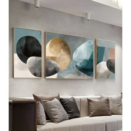 סט שלוש תמונות קנבס בגוונים של תכלת, שחור וזהב, עם צורות גאומטריות וקווים מעגליים, תלוי מעל ספה בחלל מגורים מודרני.          Ask ChatGPT