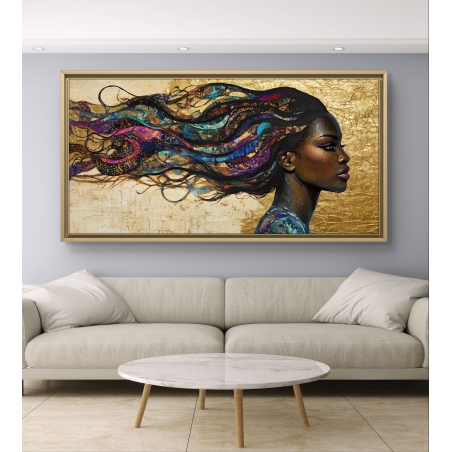 תמונת קנבס לרוחב של אישה כהת עור עם שיער צבעוני מתעופף על רקע זהב, תלויה מעל ספה בגוון שמנת.