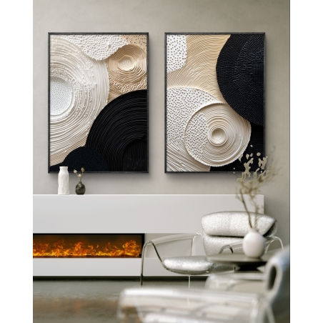 זוג תמונות קנבס עם הדפס חלק דמוי תלת־ממד בעיצוב מופשט של מעגלים בגווני בז', לבן ושחור, תלוי על קיר מעל ספה מודרנית בגוון חום־אפור.